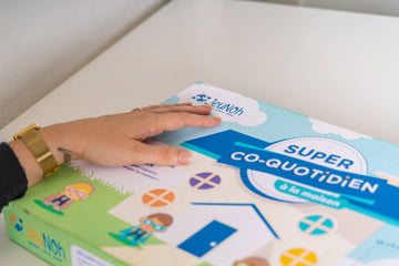 Enfant jouant avec un jeu éducatif inclusif adapté, entouré de supports visuels et d’un professionnel.