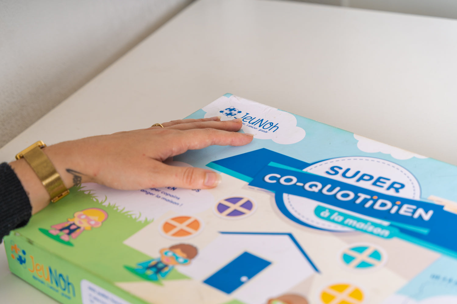 Enfant jouant avec un jeu éducatif inclusif adapté, entouré de supports visuels et d’un professionnel.