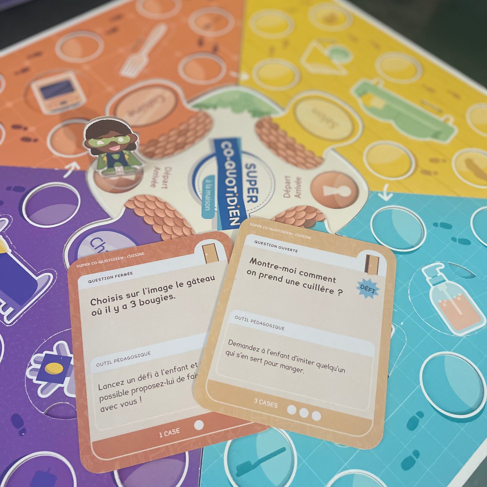 Famille jouant ensemble avec Super Co-quotidien, Mini-quotidien École, Cartes Petit Héros et Tableau de routine magnétique, partageant des moments de complicité et de développement des enfants.